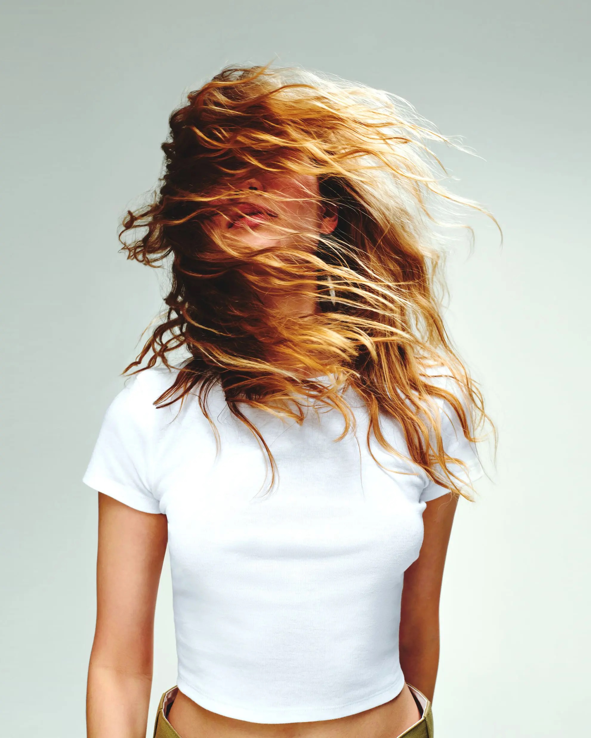 blonde woman dancing whit hair over her face wearing the BELLA+CANVAS 1010 solid white baby rib tee